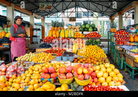Ambato, Ecuador, Dicembre 20, 2017: donna ecuadoriana fruttivendola di fronte a lei visualizza di frutti tropicali in un mercato Foto Stock