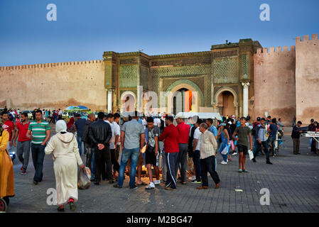 La gente sulla piazza Lahdim con Bab Mansour city gate dietro , Meknes, Marocco, Africa Foto Stock