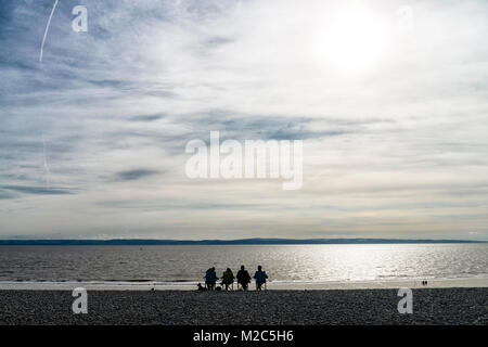 Una famiglia gode degli ultimi lanci di un tardo pomeriggio estivo sulla spiaggia di ciottoli a Knap, Barry. Foto Stock