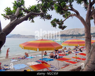 Blick auf den Strand in der Bucht von Baska auf der Insel / otok Krk. Der Untergrund hat groben Kiesa, es empfiehlt sich ein Liegestuhl. Im Hintergrund die steil ins Wasser abfallenden Felsen. Foto Stock
