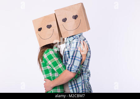 Amore giovane che coprono i loro volti con sacchetto di carta su sfondo bianco Foto Stock