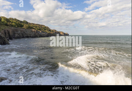 Un paesaggio marino dove un'onda si blocca sulla riva e attraversa contemporaneamente al di sopra di un'altra. Foto Stock