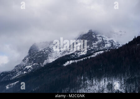 Spooky Montagne Paesaggio con picco alpino avvolta nella nebbia e nuvole Foto Stock