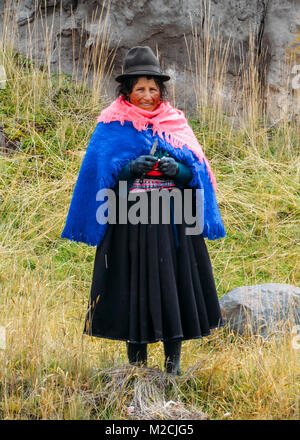 Chimborazo, Ecuador, Dicembre 20, 2017: tradizionalmente vestiti donna ecuadoriana sbucciare l'aglio sul lato di una strada Foto Stock