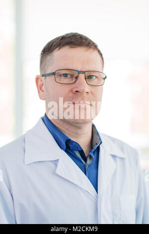 Ritratto di fiducioso maschio maturo chirurgo in piedi con le braccia incrociate in ospedale Foto Stock