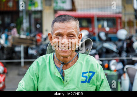 La felicità: gioiosa, accogliente locale Cambogiana Cyclo Tour della città di risciò ciclo driver con cattivo denti in una camicia verde a Phnom Penh, capitale della Cambogia Foto Stock