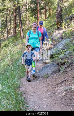 Kittredge, Colorado - Adam Hjermstad Jr., 3, porta una bottiglia di acqua come egli conduce la sua madre e nonna su una escursione sul punto panoramico sentiero. Foto Stock