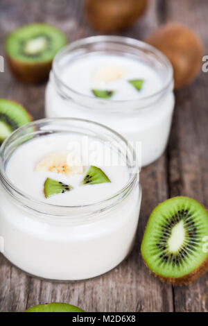 Yogurt con kiwi su uno sfondo di legno. Una gustosa prima colazione. Mangiare sano. Foto Stock