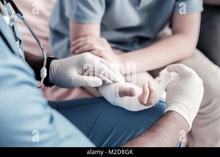 Chiusura del lavoratore medico del bendaggio mano di teen boy Foto Stock