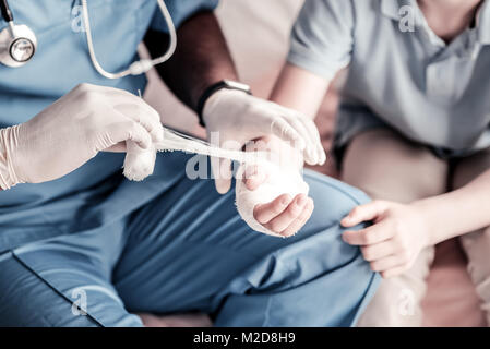 Su scala di guardare il medico del bendaggio braccio Foto Stock