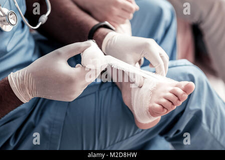 Su scala di guardare il medico del bendaggio piede Foto Stock