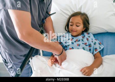 Medico tenendo la mano della ragazza nel letto di ospedale Foto Stock