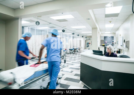 I medici spingendo il paziente in ospedale gurney Foto Stock
