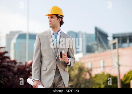 Imprenditore ispanica a bere caffè e portante blueprint all'aperto Foto Stock