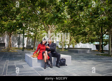 Imprenditore mostra telefono cellulare per imprenditrice a park Foto Stock