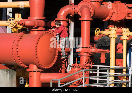 Ragazzo arrampicate sulle tubazioni del gas di vecchi lavori in lavori Gas Park, Seattle, Washington, Stati Uniti d'America Foto Stock