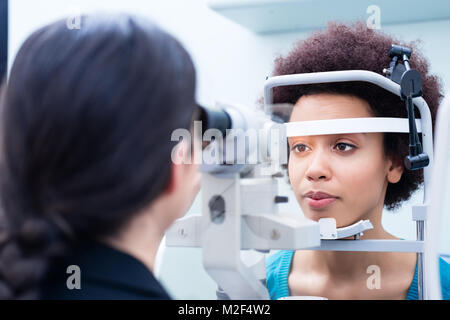 Ottico misura le donne gli occhi con rifrattometro