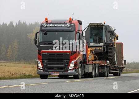 KOSKI TL, Finlandia - 29 settembre 2017: Volvo FH semi rimorchio di Kosken Autokeskus trasporta Sampo Rosenlew mietitrebbia lungo l'autostrada su un nebbioso giorno di un Foto Stock
