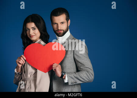 Giovane Azienda a forma di cuore ad pezzo di carta isolato su blu Foto Stock