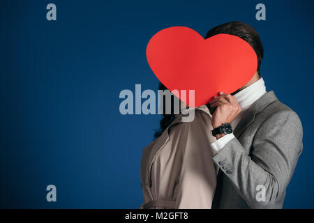 Due facce di copertura con cuore pezzo sagomato di carta isolato su blu Foto Stock