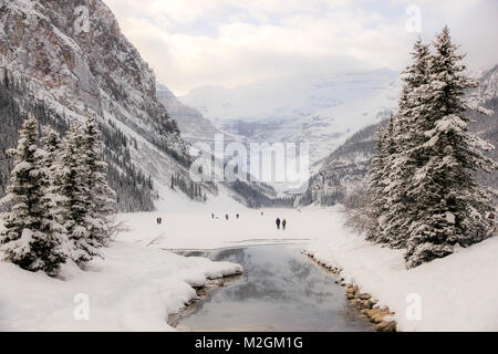 Lago ghiacciato di Louise nel Parco Nazionale di Banff, coperto di neve. Alcuni escursionisti su di esso. Il Canada in inverno. Foto Stock