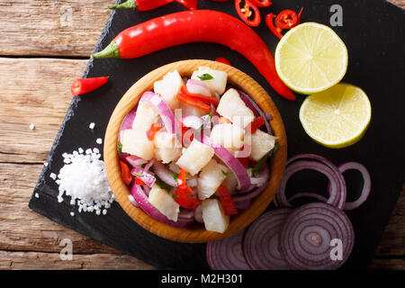 Preparate di fresco ceviche di pesce bianco con le cipolle e i peperoni di close-up in una ciotola sul tavolo. parte superiore orizzontale vista da sopra Foto Stock