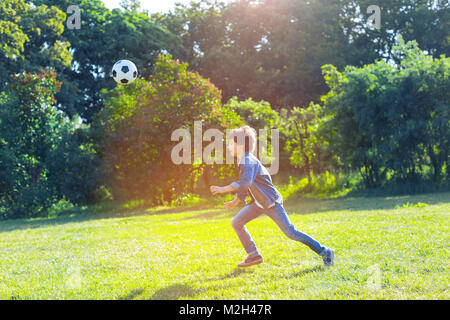 Active teen boy a giocare a calcio all'aperto Foto Stock