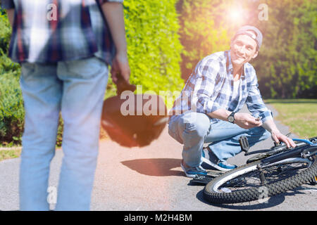 Figlio guardando padre bicicletta di fissaggio in posizione di parcheggio Foto Stock