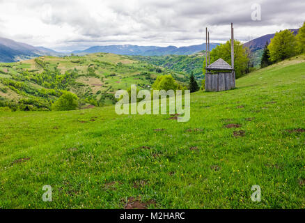 Legno vecchio capannone di fieno sul pendio erboso. bellissimo scenario di montagna zona rurale in primavera Foto Stock