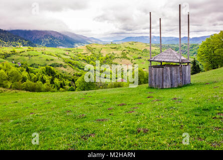 Legno vecchio capannone di fieno sul pendio erboso. bellissimo scenario di montagna zona rurale in primavera Foto Stock