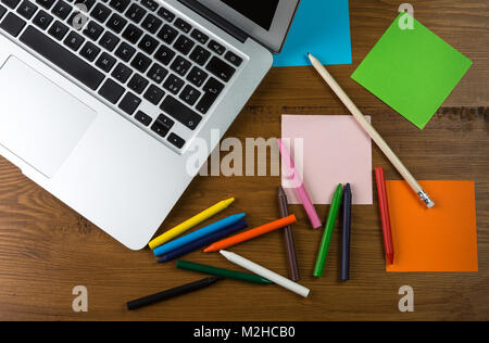 Bianco colorato post-it con forniture per ufficio su un tavolo di legno. Vista da sopra con un post-it per lo spazio di copia Foto Stock