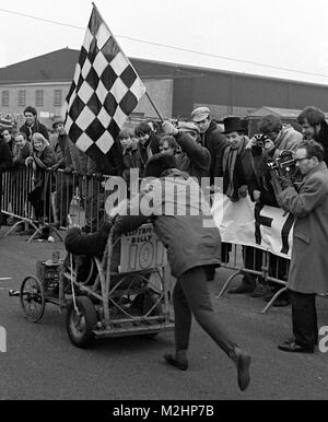 Cinema cinegiornale cameraman con wind-up cinepresa cattura le fasi finali del 1968 National 24 ore auto pedale gara a Whitchurch aeroporto, Bristol. La gara, svoltasi round-the-clock dal 1 al 2 marzo, era parte dell'Università di Bristol Rag settimana e ha attirato 100 team che hanno costruito le proprie voci in collegi, aziende e università in tutto il Regno Unito. L'evento di beneficenza è stata supportata da Innes Ireland, motoring giornalista ed ex Formula Uno racing driver, chi ha cominciato e finito e ha presentato i premi. Foto Stock