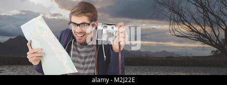 Uomo in viaggio con la macchina fotografica e la mappa nella parte anteriore del paesaggio Foto Stock