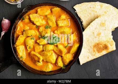 Indian pollo al curry sulla pietra nera dello sfondo. Vista superiore, piatto laici. Close up Foto Stock