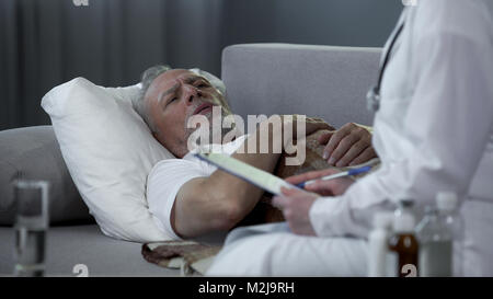 Medico donna la prescrizione di farmaci di vecchio uomo malato che giace nel letto di casa, stock footage Foto Stock