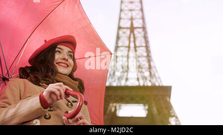 Felice lady in piedi sotto ombrellone a Parigi, sorridente e di attesa per data, stock footage Foto Stock