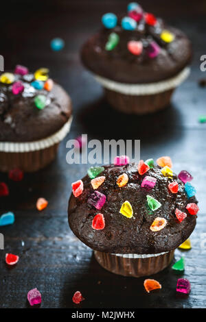 Deliziosi muffin aChocolate con caramelle sul tavolo di legno. Foto Stock