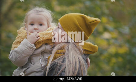 Piuttosto piccola figlia con la sua mamma passeggiate nel parco di autunno Foto Stock