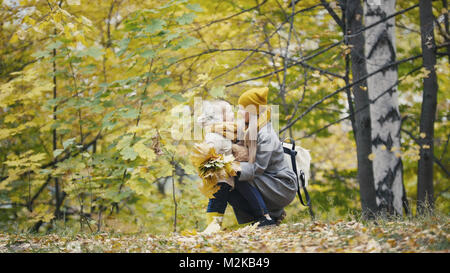 Piuttosto piccola figlia con la sua mamma passeggiate nel parco di autunno - abbraccia Foto Stock