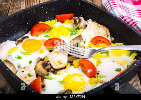 Uova fritte, pomodori, prosciutto, funghi in padella Foto Stock