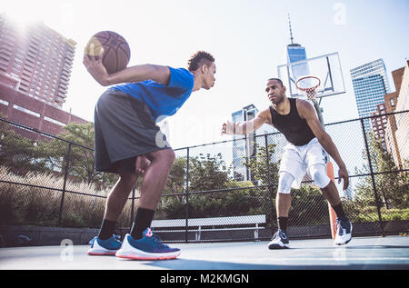 Due street basket i giocatori che giocano duro su corte Foto Stock