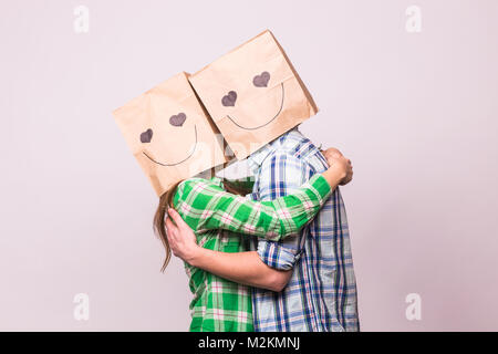 Amore giovane che coprono i loro volti con sacchetto di carta su sfondo bianco. Foto Stock