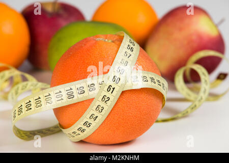 Frutti e nastro di misurazione. Concetto di dieta. Cibo Vegan sfondo. Foto Stock