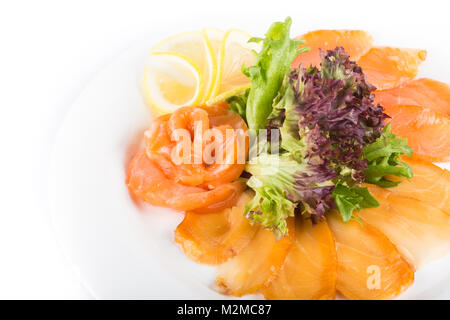 Un assortimento di pesce su una piastra con lattuga e limone su uno sfondo bianco. Un piatto di pesce isolato assortiti Foto Stock