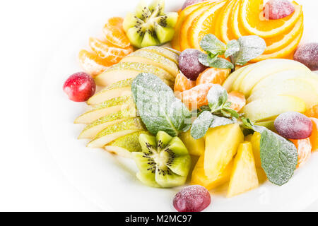 Un piatto di frutta, isolato. apple, mandarino, kiwi, uva, menta, pera, mela, ananas. Macedonia di frutta nella piastra di close-up Foto Stock