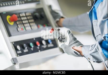 Tornio CNC Pannello di controllo. Lavoratore con il telecomando collegato tramite filo di funzionamento funzioni CNC. Foto Stock