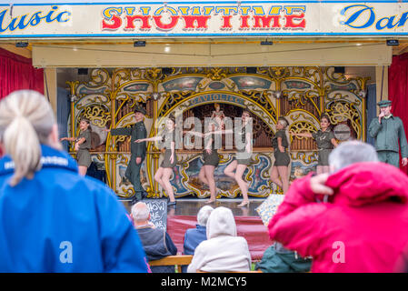 Guarda gli astanti giovani ballerine in abbigliamento militare preforma sulla fiera organo, Masham, North Yorkshire, Regno Unito Foto Stock