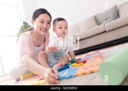 La madre gioca con il baby sitting room Foto Stock