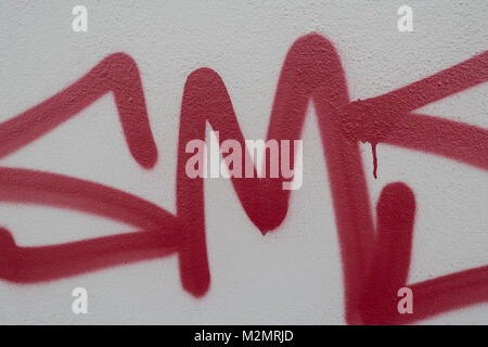 In rosso le lettere graffiti su un muro grigio Foto Stock