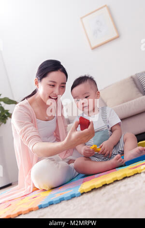 La madre gioca con il baby sitting room Foto Stock